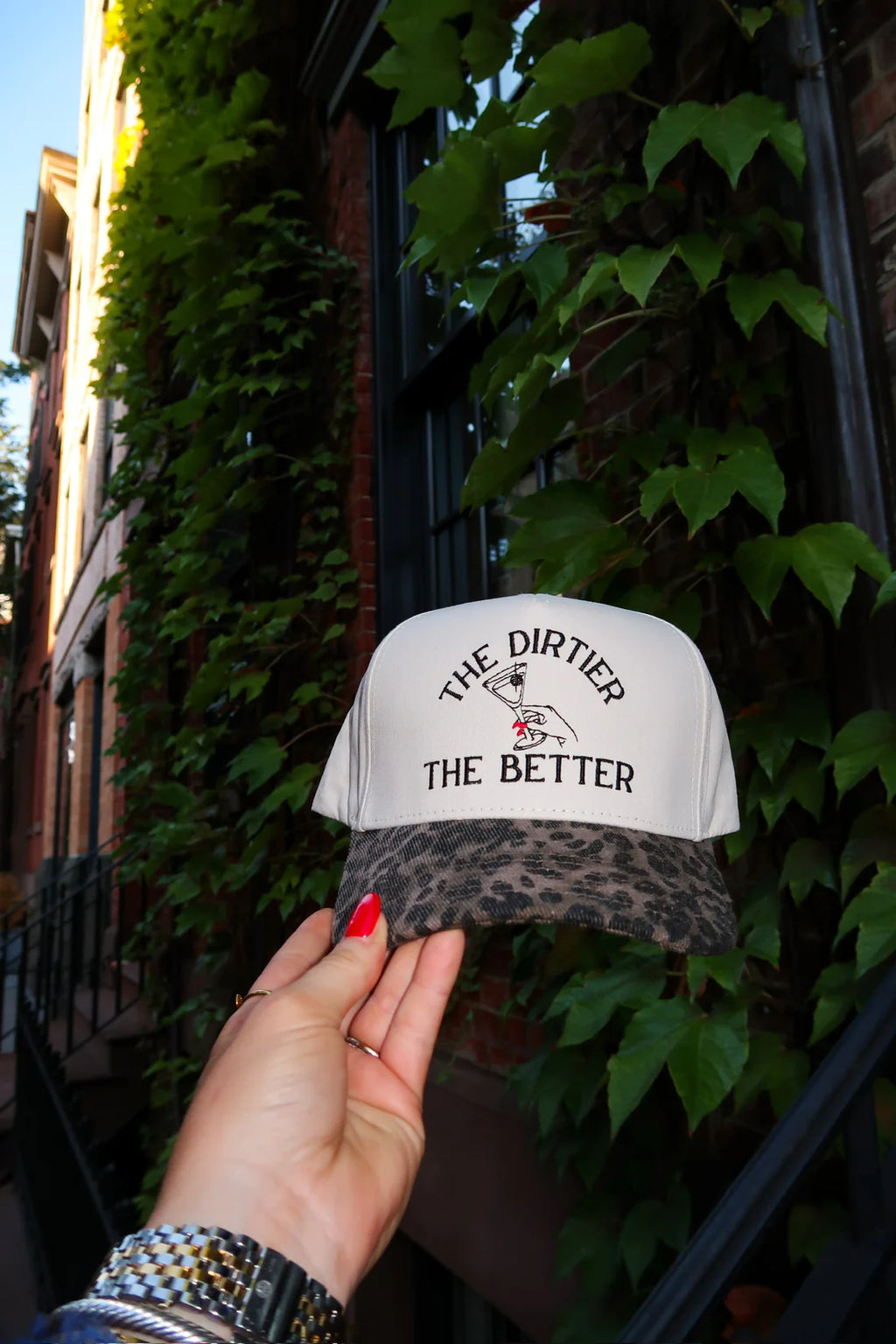 Hand holding a cap with text against a leafy background
