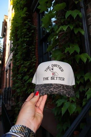 Hand holding a cap with text against a leafy background