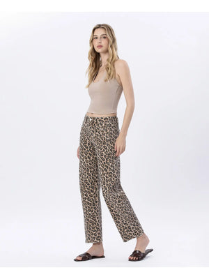 Woman wearing a beige top and leopard print pants on a white background