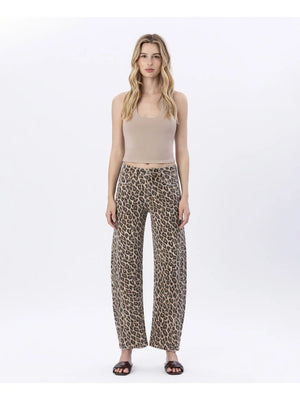 Woman wearing a beige tank top and leopard print pants on a white background
