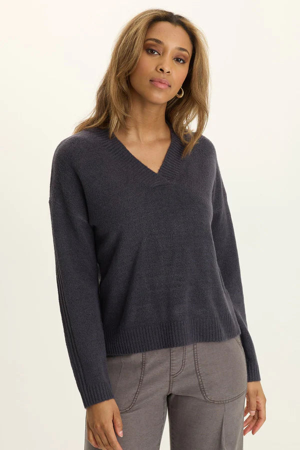 Woman wearing a dark gray sweater and gray pants on a white background