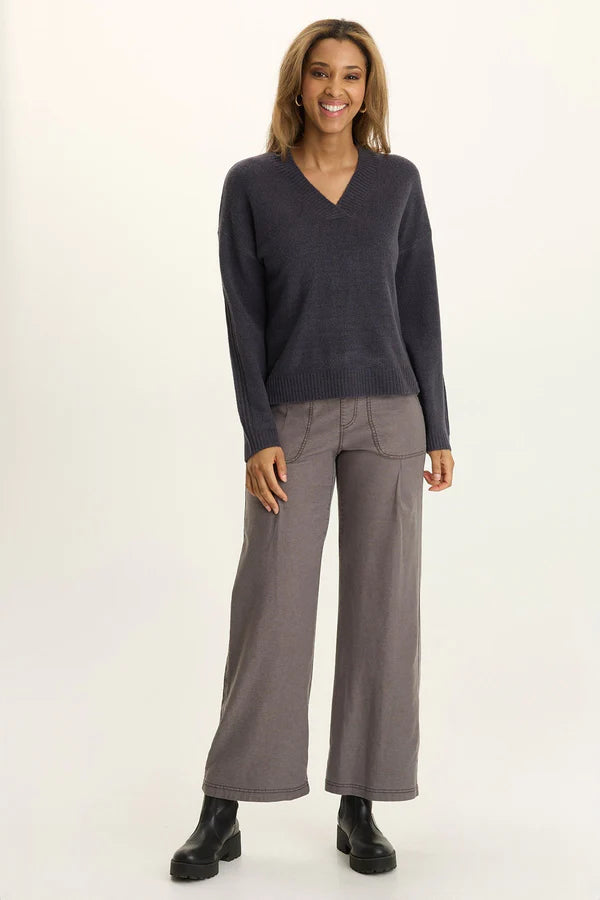 Woman wearing a dark gray sweater and light gray pants on a white background
