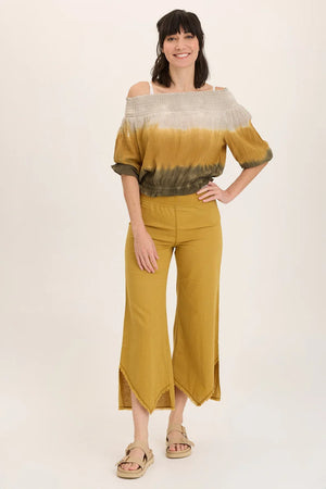 Woman wearing a yellow and green tie-dye top with wide-leg pants on a white background