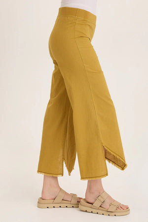 Mustard yellow pants worn by a person on a white background