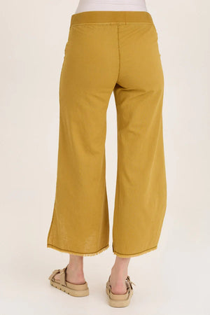 Mustard yellow pants worn by a person on a white background