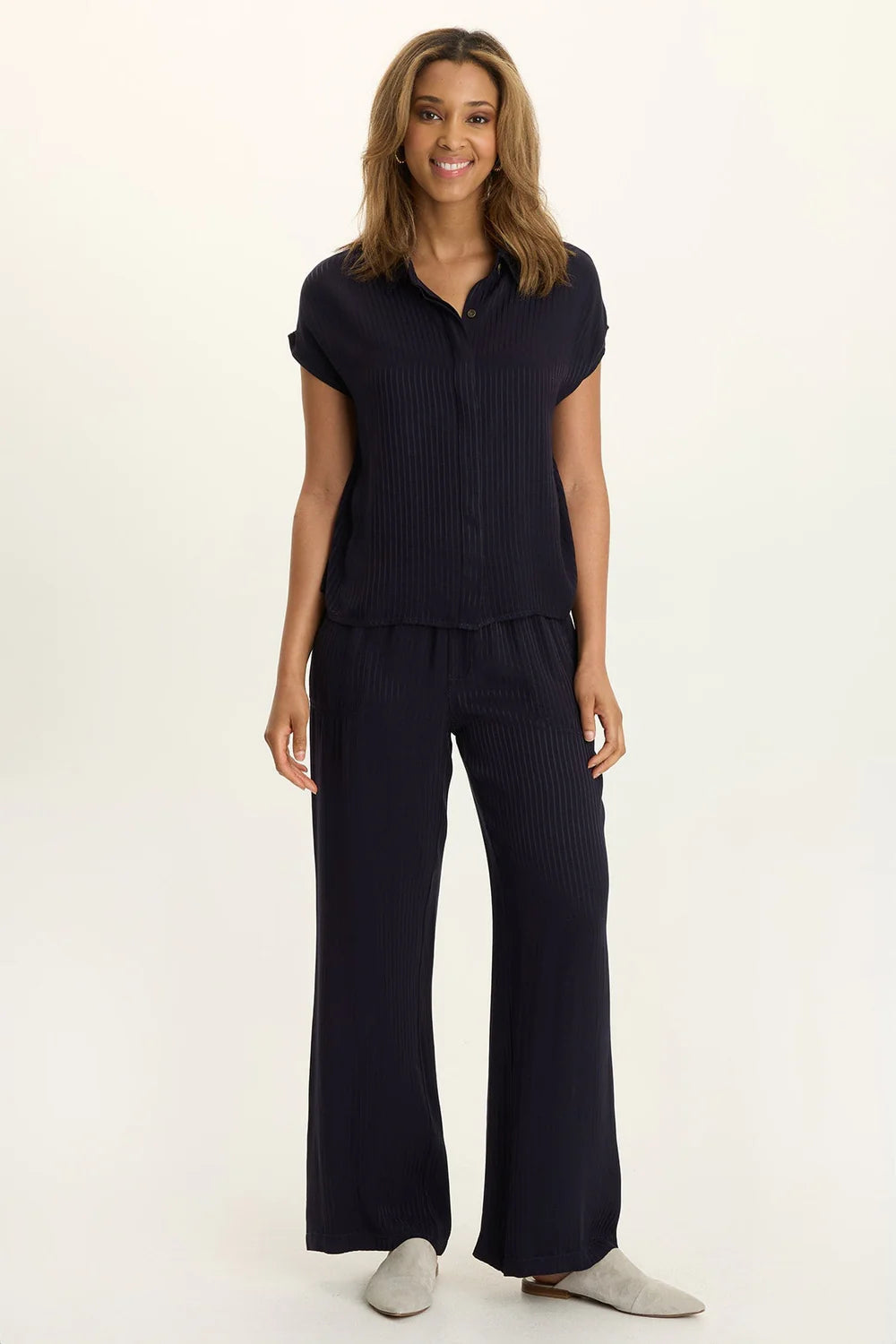 Woman wearing a navy blue outfit with a matching top and pants on a white background