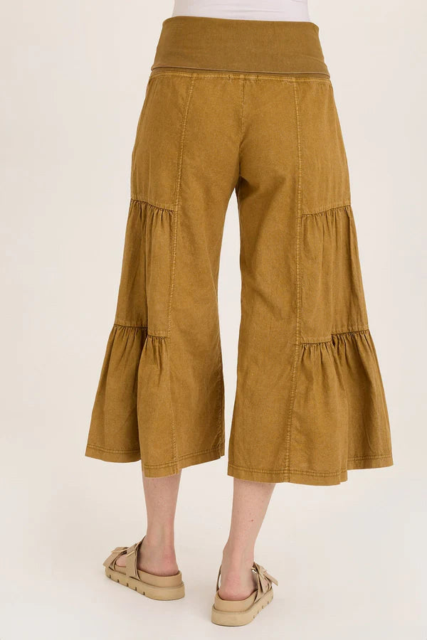 Mustard yellow tiered pants worn by a person on a white background