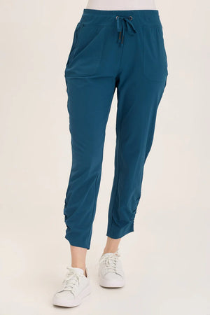 Teal jogger pants worn by a person on a white background