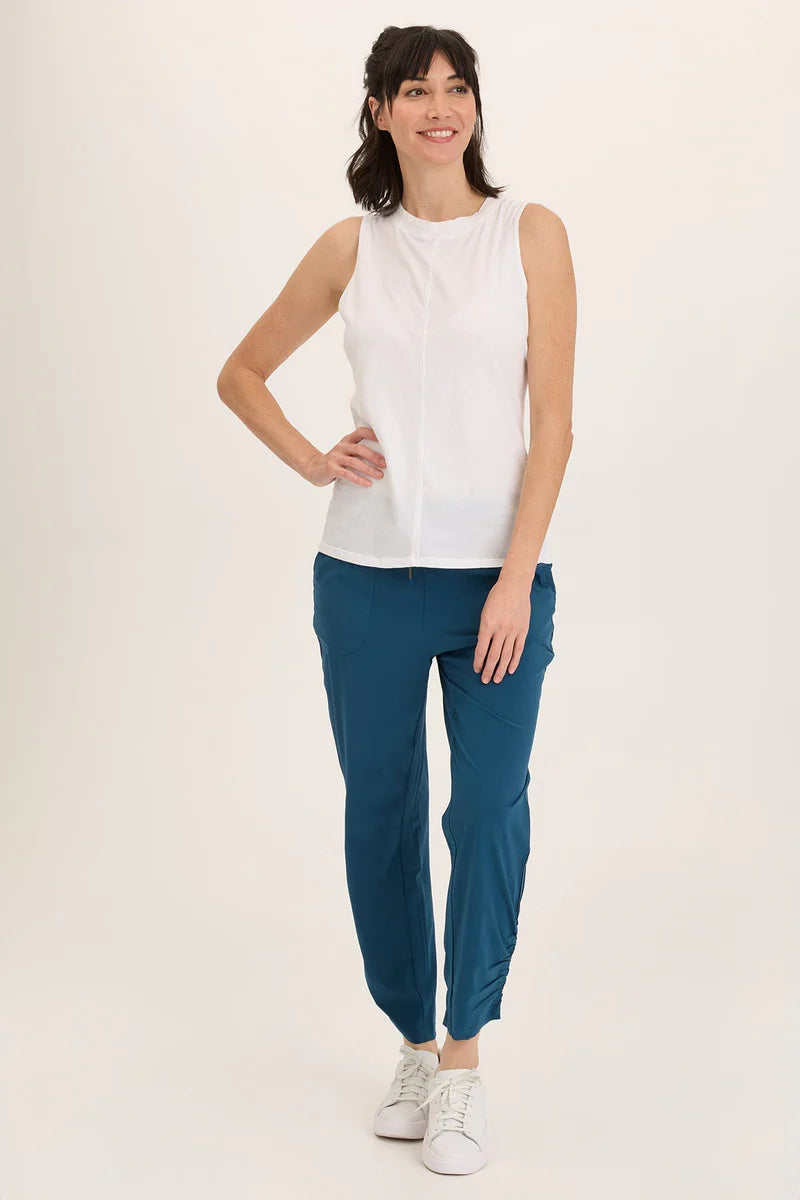 Woman wearing a white sleeveless top and blue pants on a white background
