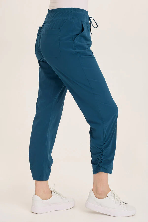 Teal jogger pants worn by a person on a beige background