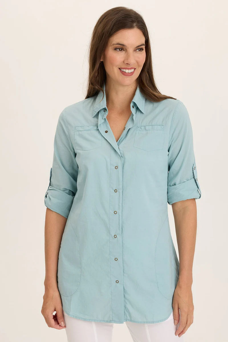 Woman wearing a light blue button-up shirt against a beige background