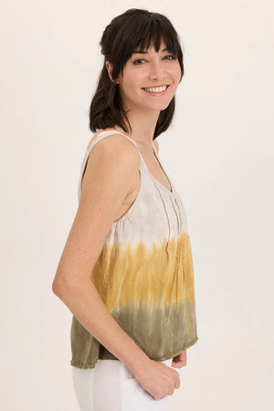 Woman wearing a sleeveless, tie-dye top with a gradient from yellow to green on a plain background.