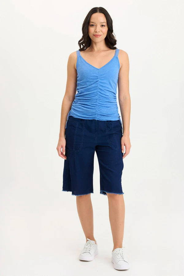 Woman wearing a blue tank top and navy capri pants on a white background