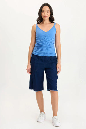 Woman wearing a blue tank top and navy capri pants on a white background