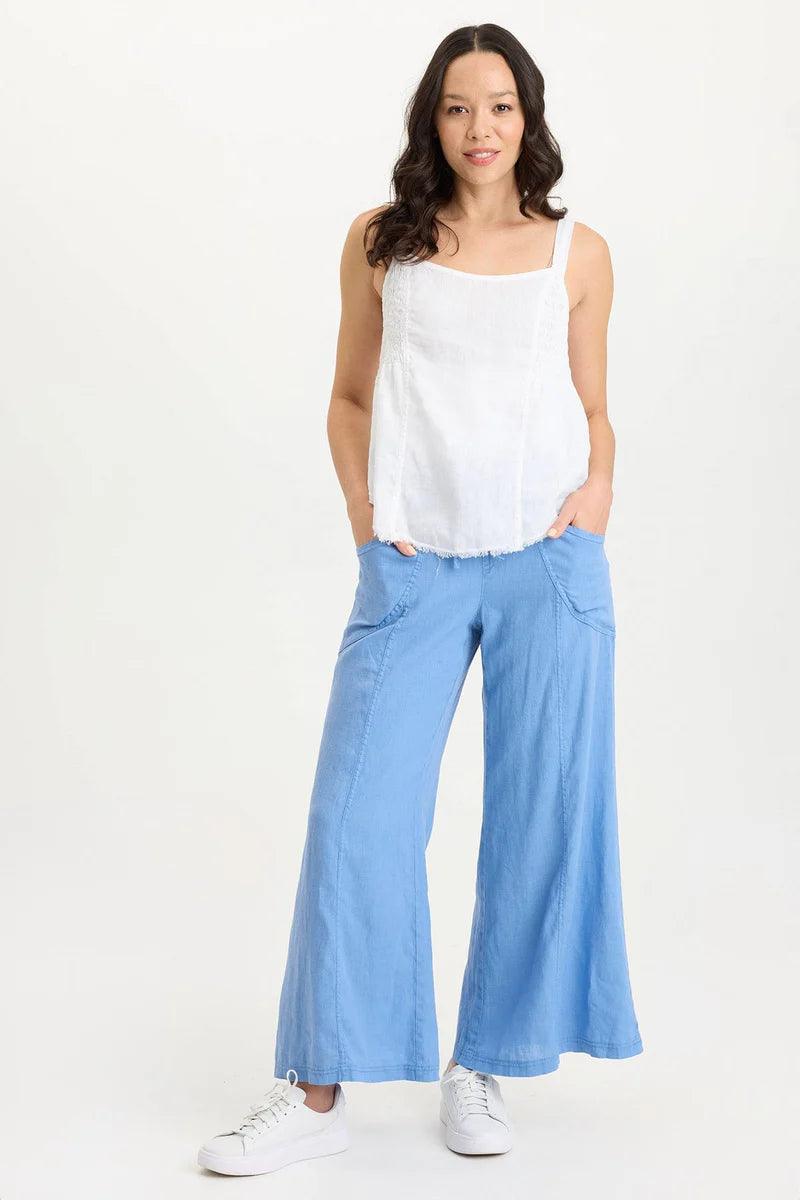Woman wearing a white top and light blue flared pants on a white background