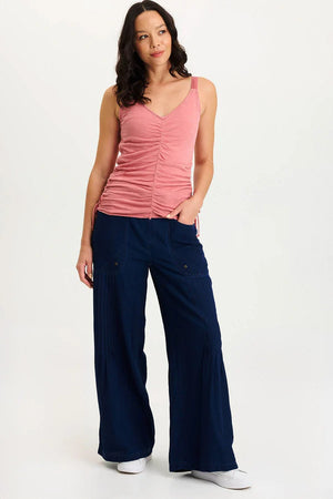 Woman wearing a pink tank top and navy wide-leg pants on a white background
