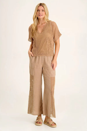 A linen pull-on waist, wide leg with a circular design, crochet leg panels, and front and back pockets make up the Tangent Pant.