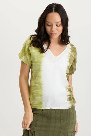 Woman wearing a tie-dye shirt with green and white pattern on a plain background