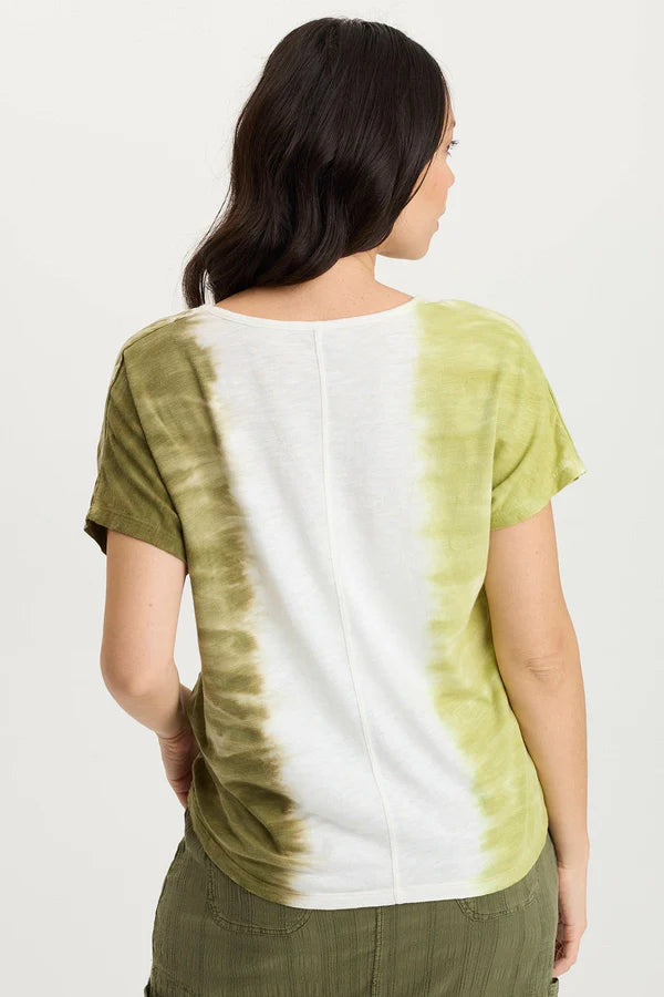 Woman wearing a tie-dye shirt with green and white pattern on a plain background