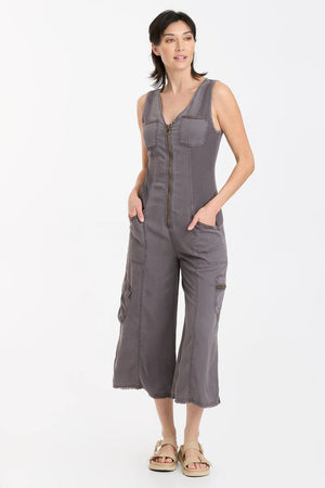 In Soft Twill, this v-neck crop jumpsuit features twill tape details throughout, plentiful pockets, antique brass hardware, a raw-edge hem, an elastic band at the center back for a contoured fit, and contrast front and back ribbed side panels for movement-friendly comfort.