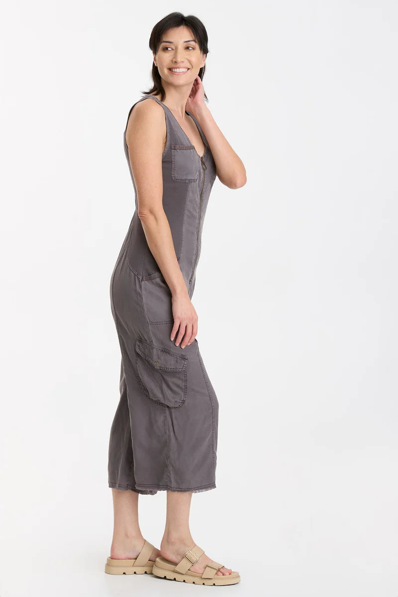 In Soft Twill, this v-neck crop jumpsuit features twill tape details throughout, plentiful pockets, antique brass hardware, a raw-edge hem, an elastic band at the center back for a contoured fit, and contrast front and back ribbed side panels for movement-friendly comfort.