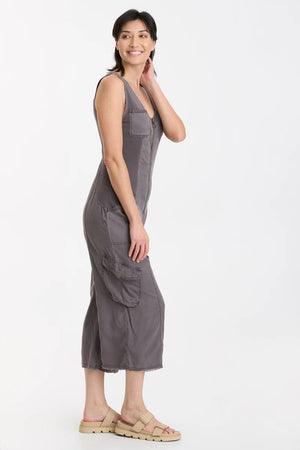 In Soft Twill, this v-neck crop jumpsuit features twill tape details throughout, plentiful pockets, antique brass hardware, a raw-edge hem, an elastic band at the center back for a contoured fit, and contrast front and back ribbed side panels for movement-friendly comfort.