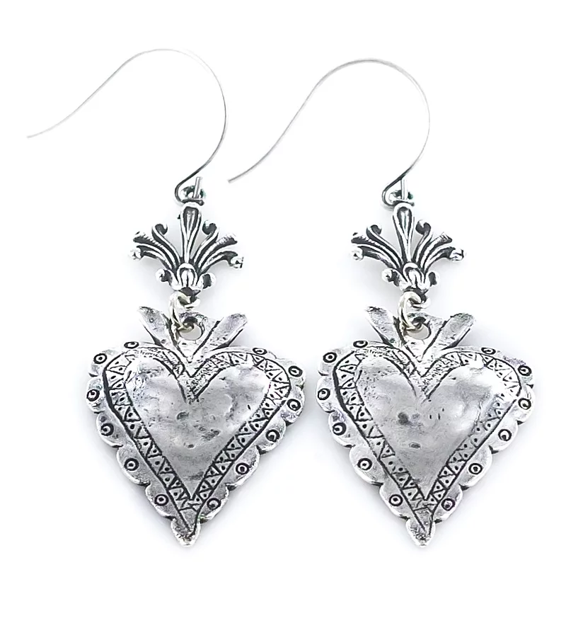 A pair of silver heart-shaped earrings with intricate patterns and dangling embellishments.