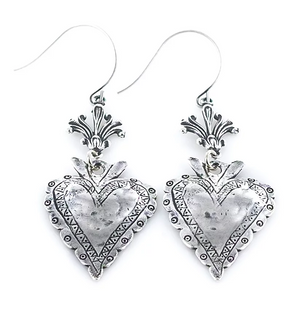 A pair of silver heart-shaped earrings with intricate patterns and dangling embellishments.